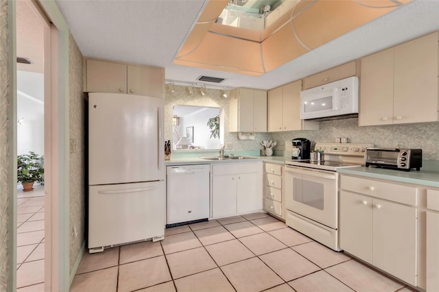 kitchen with white appliances, sink, light tile floors, cream cabinetry, and tasteful backsplash