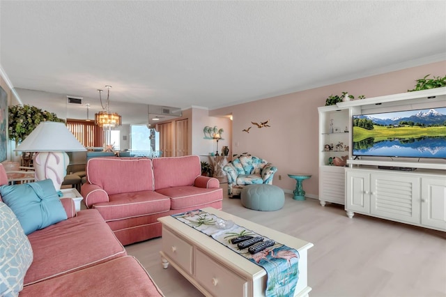 living room featuring an inviting chandelier, ornamental molding, and light wood-type flooring