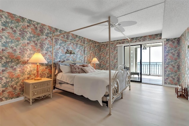 bedroom featuring a textured ceiling, ceiling fan, access to outside, and light hardwood / wood-style flooring