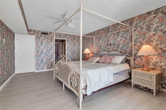 bedroom with a textured ceiling, ceiling fan, and hardwood / wood-style flooring