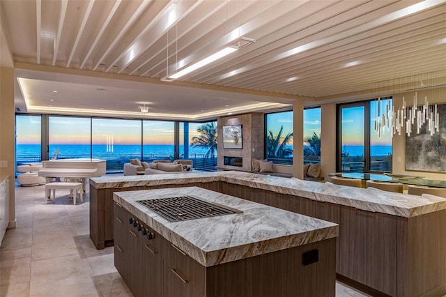 kitchen with a spacious island, light tile patterned floors, a water view, and a fireplace