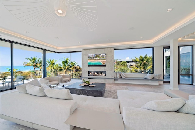 living room featuring a water view, a tile fireplace, and floor to ceiling windows