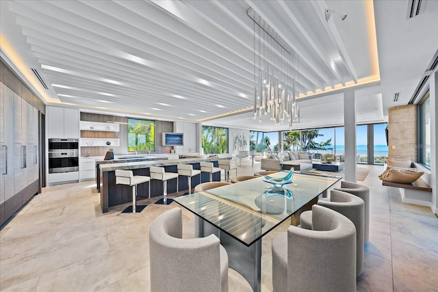 dining area with a water view, floor to ceiling windows, and a chandelier