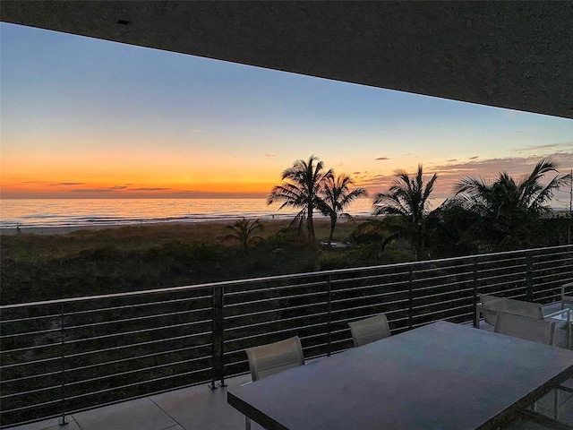 patio terrace at dusk with a view of the beach and a water view