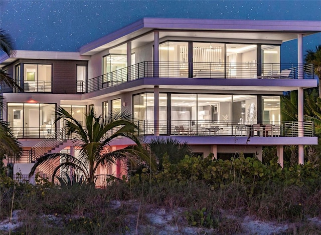 back house at twilight featuring a balcony