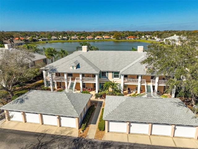 view of front of house with a garage, a balcony, and a water view