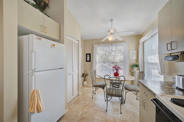 kitchen with a textured ceiling, range, white fridge, ceiling fan, and light tile floors