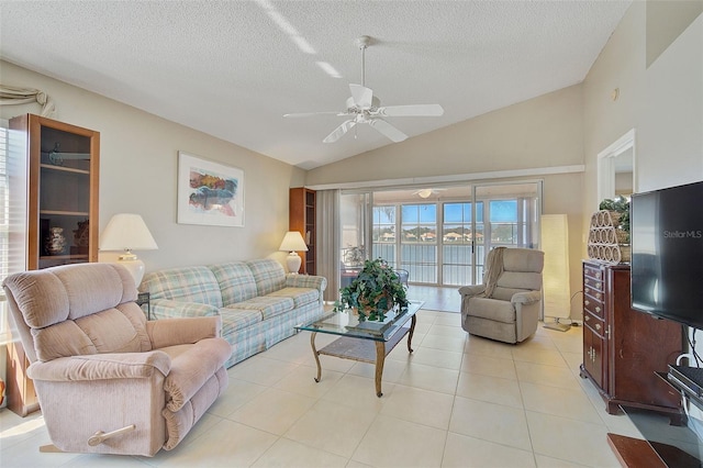 tiled living room featuring ceiling fan, vaulted ceiling, a textured ceiling, and a water view