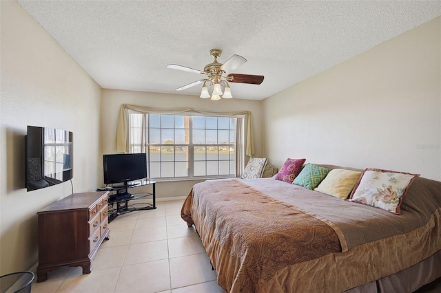 tiled bedroom featuring ceiling fan and a textured ceiling