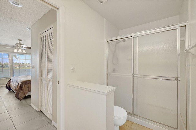 bathroom with tile flooring, an enclosed shower, a water view, ceiling fan, and toilet