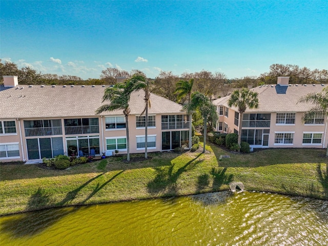 back of house featuring a lawn and a water view