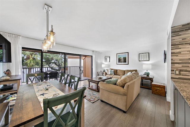 living room featuring a chandelier, wood walls, and light hardwood / wood-style floors