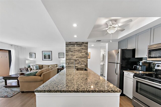 kitchen featuring backsplash, an island with sink, appliances with stainless steel finishes, and sink