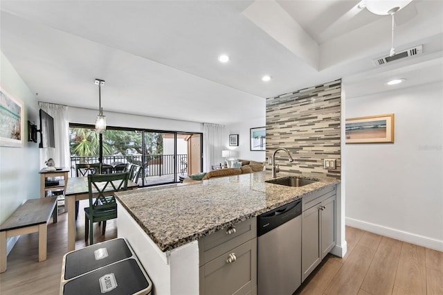 kitchen with gray cabinetry, sink, stainless steel dishwasher, light stone counters, and tasteful backsplash