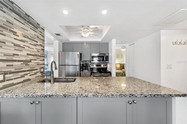 kitchen with ceiling fan, sink, light stone counters, appliances with stainless steel finishes, and tasteful backsplash