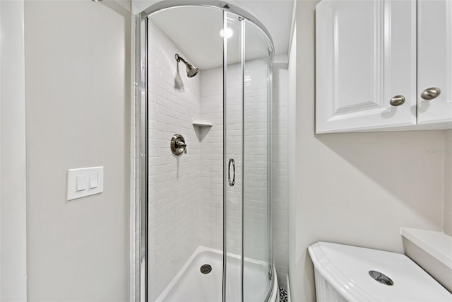 bathroom with toilet and a shower with shower door