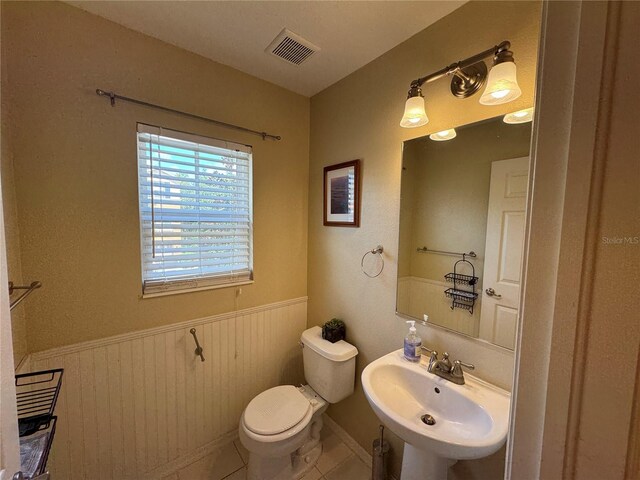 bathroom with visible vents, toilet, wainscoting, a sink, and tile patterned flooring