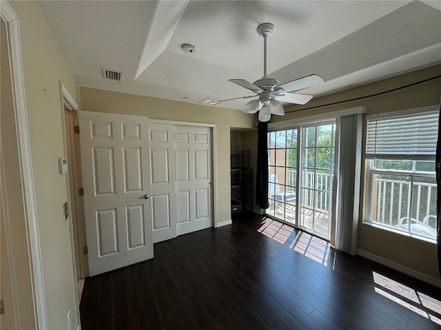 unfurnished bedroom featuring a textured ceiling, dark wood-style flooring, visible vents, access to outside, and a closet