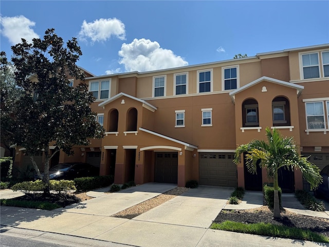 multi unit property featuring a garage, driveway, and stucco siding