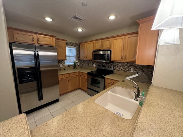 kitchen with a sink, visible vents, light countertops, appliances with stainless steel finishes, and backsplash