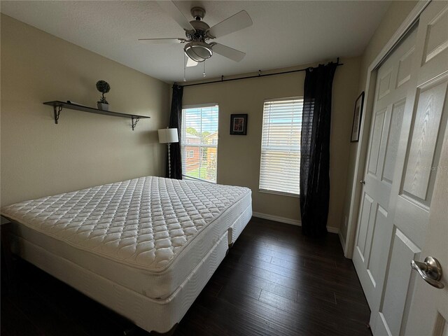 bedroom with baseboards, a ceiling fan, and dark wood-type flooring
