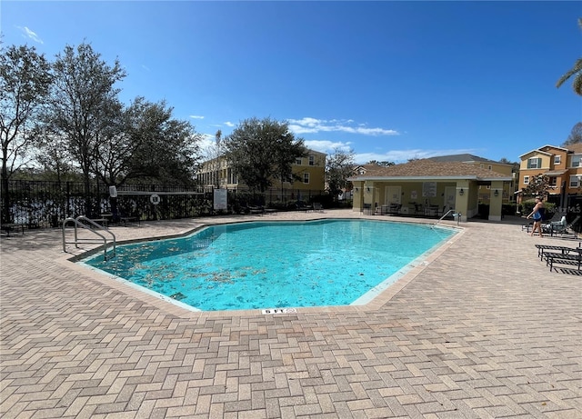 community pool with a patio area and fence