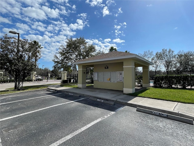 view of community featuring uncovered parking, fence, and mail area