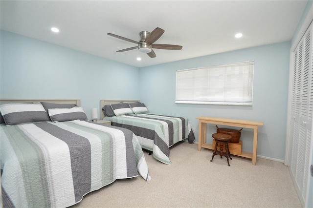 bedroom with ceiling fan, light carpet, and a closet