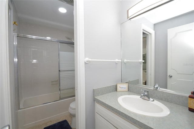 full bathroom featuring toilet, combined bath / shower with glass door, and vanity