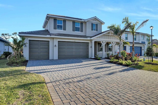 view of front of home with a front yard, decorative driveway, a garage, and stucco siding