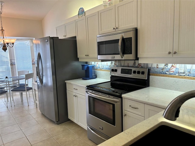 kitchen with stainless steel appliances, light stone countertops, white cabinetry, hanging light fixtures, and an inviting chandelier