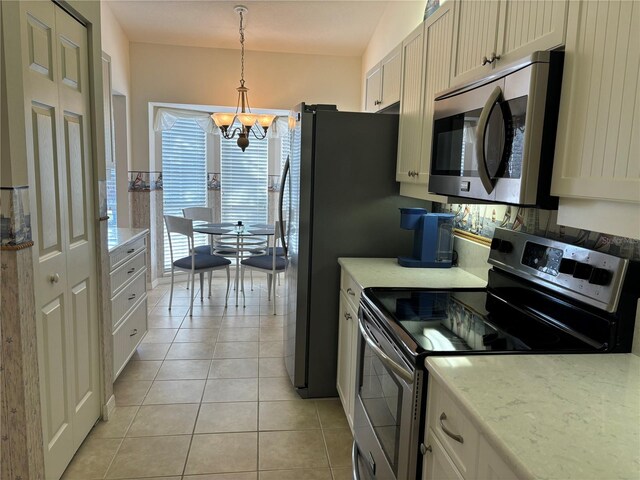 kitchen featuring a chandelier, pendant lighting, stainless steel appliances, light tile floors, and white cabinets