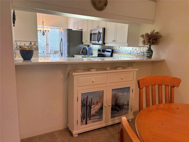 kitchen featuring white cabinetry, backsplash, an inviting chandelier, appliances with stainless steel finishes, and carpet flooring