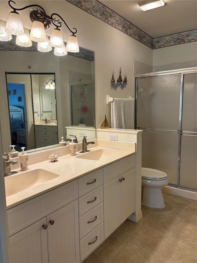 bathroom featuring toilet, large vanity, a shower with shower door, double sink, and tile flooring