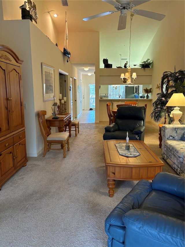 carpeted living room with high vaulted ceiling and ceiling fan with notable chandelier