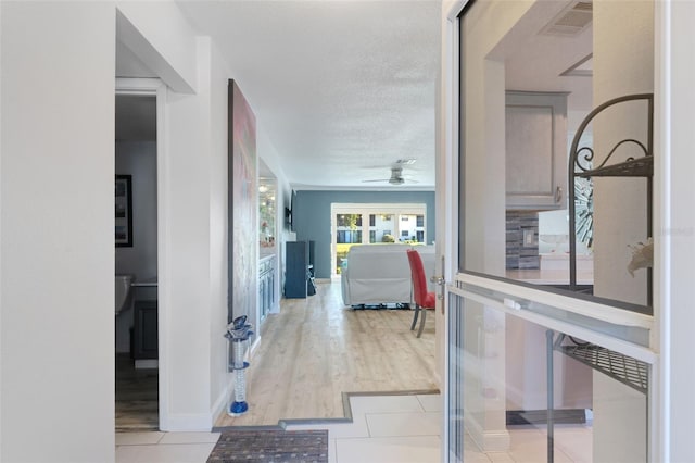 corridor with light tile floors, a textured ceiling, and french doors