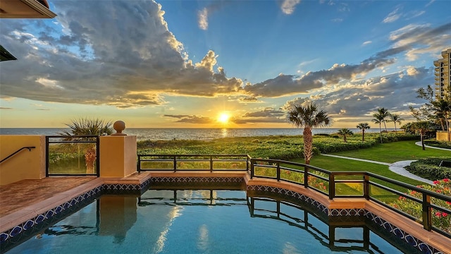 pool at dusk with a yard and a water view