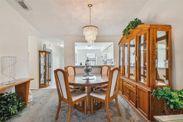 carpeted dining space with an inviting chandelier