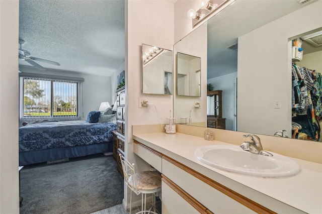 bathroom with ceiling fan, a textured ceiling, and vanity