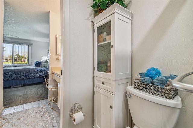 bathroom with tile patterned floors, a textured ceiling, vanity, and toilet