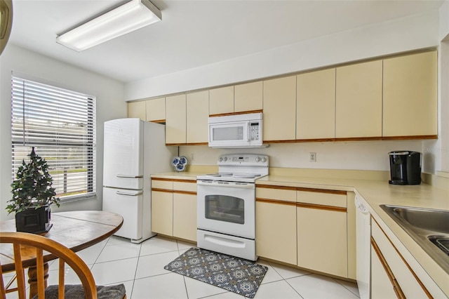 kitchen with white appliances, sink, cream cabinets, and light tile patterned floors