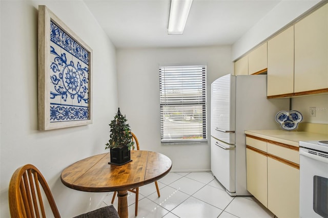 kitchen featuring cream cabinets, white appliances, and light tile patterned floors