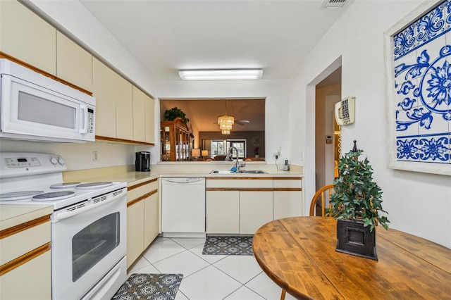 kitchen featuring a chandelier, cream cabinets, light tile patterned floors, white appliances, and sink