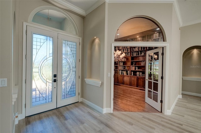 foyer entrance with ornamental molding, light hardwood / wood-style floors, and french doors