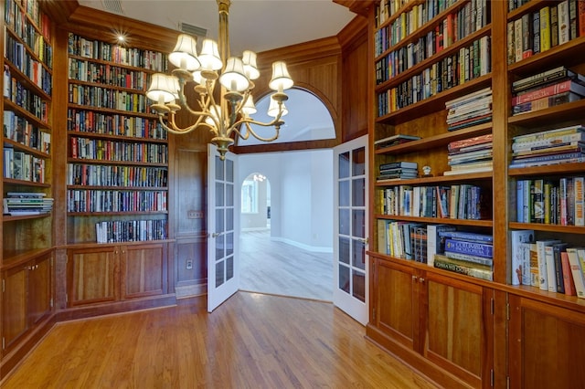 unfurnished office with built in shelves, a notable chandelier, light wood-type flooring, and french doors