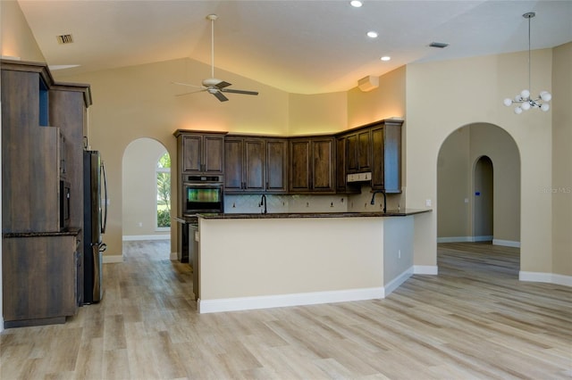 kitchen with high vaulted ceiling, stainless steel refrigerator, and light wood-type flooring