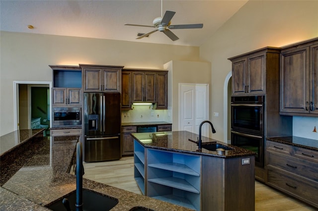 kitchen with stainless steel appliances, sink, a kitchen island with sink, and light wood-type flooring