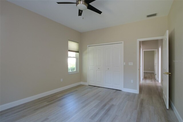 unfurnished bedroom featuring ceiling fan, a closet, and light wood-type flooring