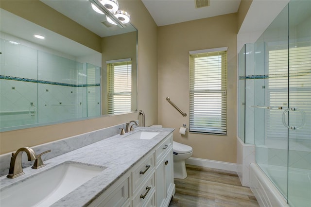 full bathroom with double sink vanity, toilet, a wealth of natural light, and hardwood / wood-style flooring