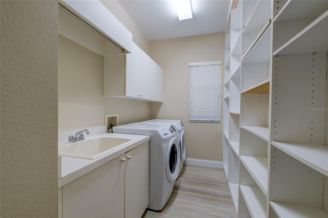 washroom featuring cabinets, sink, light wood-type flooring, washer and clothes dryer, and washer hookup